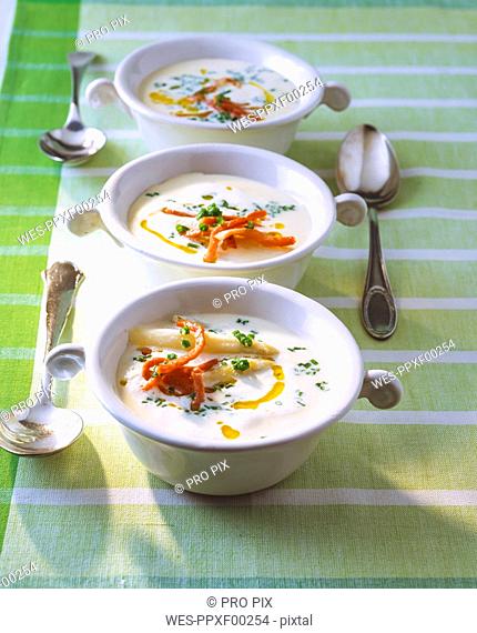 Asparagus soup with chervil and ham in bowls on table