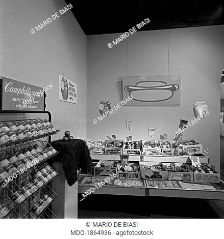 Foreshortening view of the exhibition American Supermarket at Il segno art gallery. There are a Campbell's Soup stand made by Andy Warhol