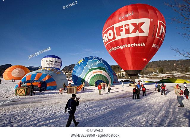 hot-air balloon festival on a snow field with several balloons being prepared for the start and a lot of spectators, Germany, Bavaria, Allgaeu, Oberstdorf