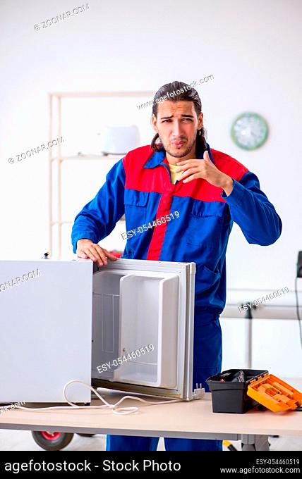 The young male contractor repairing refrigerator at workshop