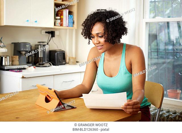 Mixed race woman using digital tablet in kitchen