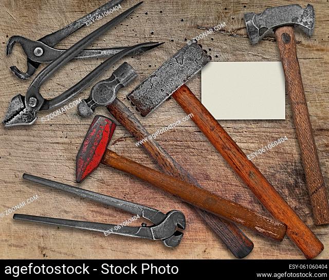 vintage blacksmith or metalwork tools over wooden bench, business card for your text