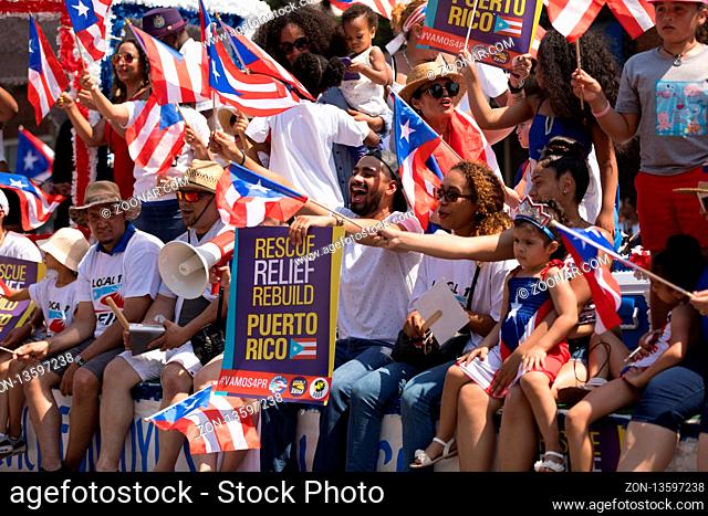Chicago, Illinois, USA - June 16, 2018: The Puerto Rican People's Parade, Puerto Rican people on top of a float celebrating waving puerto rican flags and...
