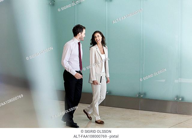 Business associates chatting while walking together in office