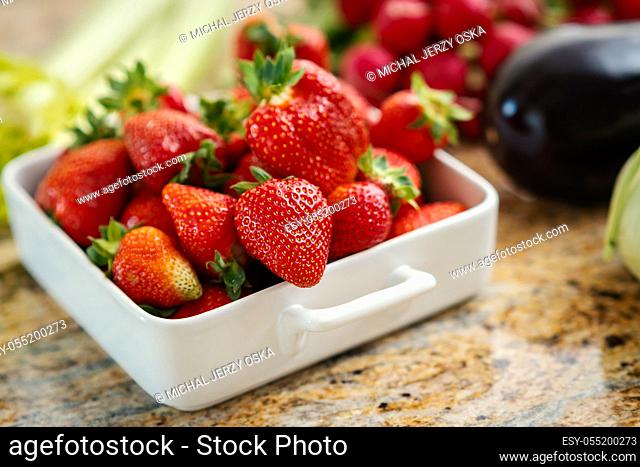 fresh red strawberries and juicy vegetables on the kitchen table