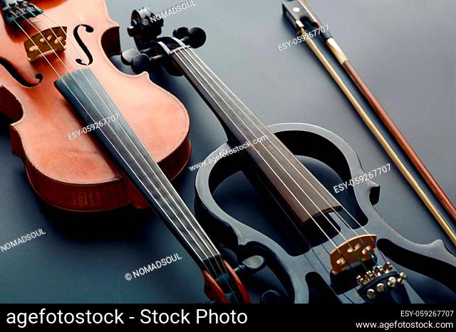 Bow, wooden retro violin and modern electric viola, closeup view, nobody. Two classical string musical instruments, black background