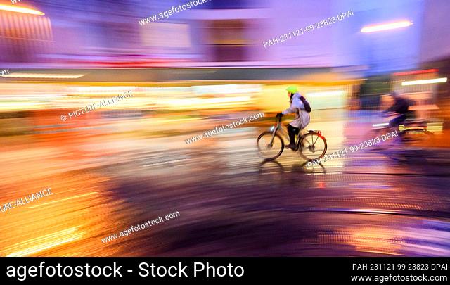 21 November 2023, Lower Saxony, Hanover: A woman rides a bicycle along Limmerstraße in the early morning (shot with slow shutter speed)