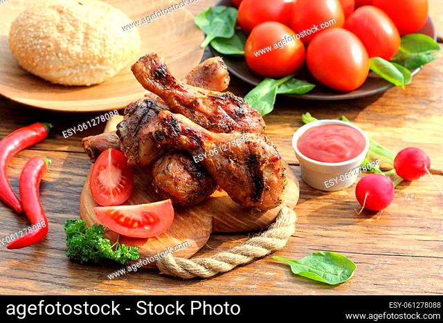 Grilled chicken legs with herbs on cutting board. Dinner background