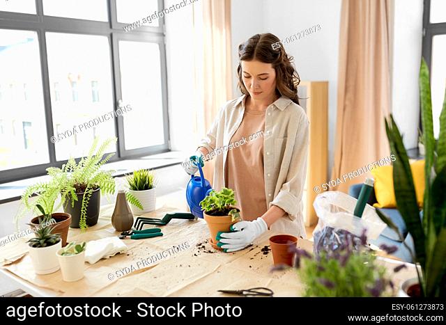 happy woman planting pot flowers at home