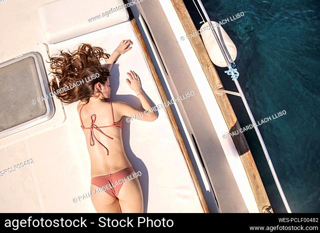 Woman wearing bikini lying down on yacht at sunny day