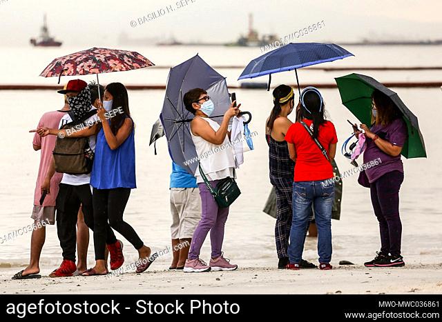 People take pictures as they flock to a portion of Manila baywalk area that was covered with crushed dolomite rocks amid rising coronavirus cases in Manila
