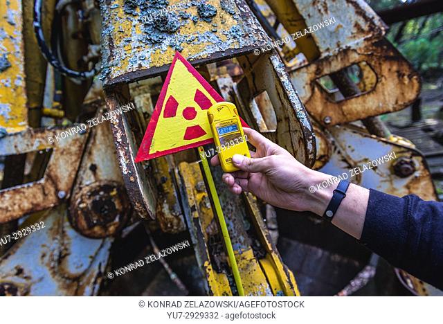 Tourist examine irradiated scrap bucket in Pripyat city of Chernobyl Nuclear Power Plant Zone of Alienation around nuclear reactor disaster, Ukraine