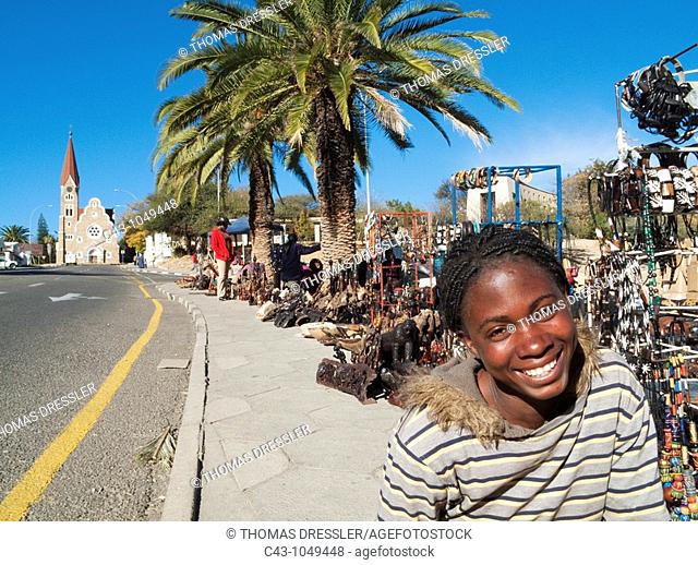 Namibia - Vendor at the well-known open-air souvenir market in the centre of Namibia's capital Windhoek with the famous Christuskirche Church of Christ in the...