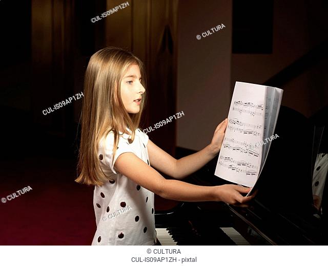 Girl choosing sheet music for piano