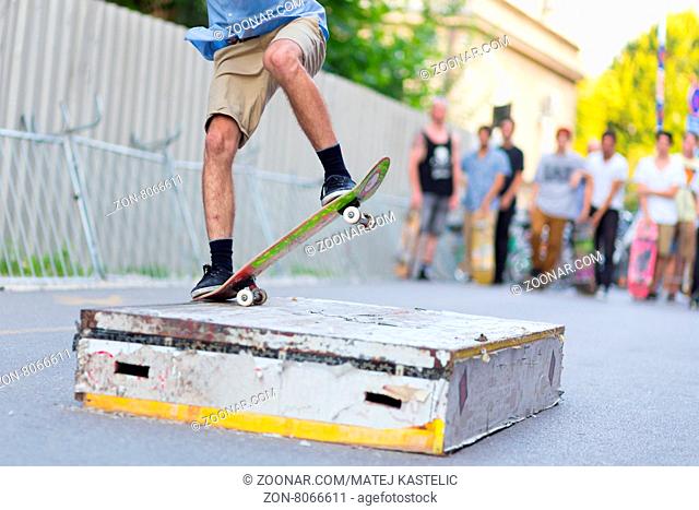 Young skateboarder skateboarding on the street. Skateboarding legs doing slide trick on object. Group of friends cheering in the background