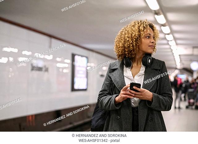 Woman with cell phone waiting in subway station