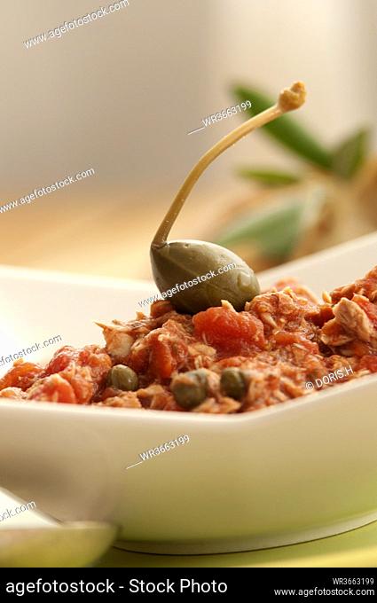 Bowl of tomato sauce with capers on wooden table, close up
