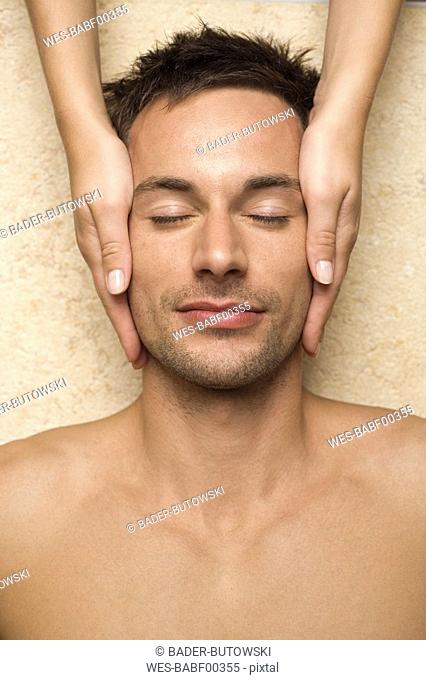 Germany, man receiving facial massage, close-up