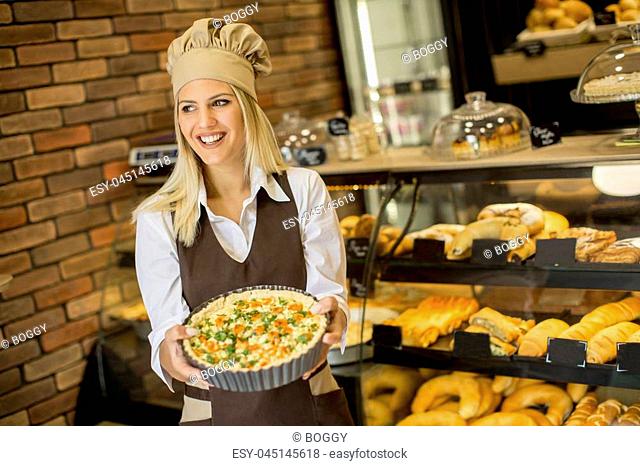 Pretty young woman with quiche lorraine in the bakery