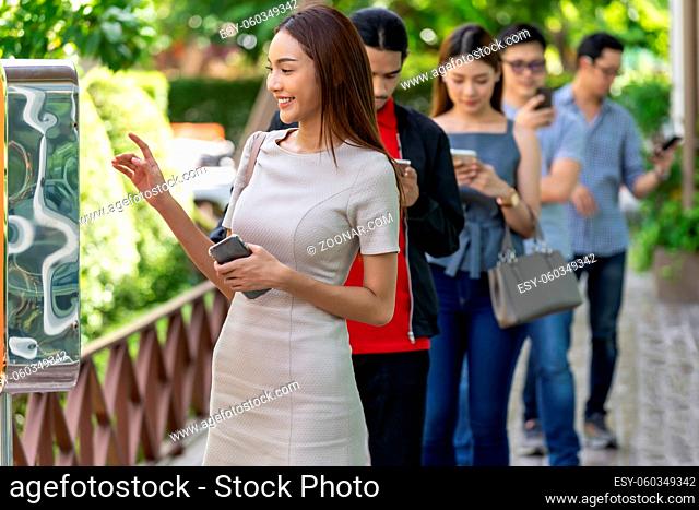 Asian woman using kiosk of food ordering with social distance queue in line before getting in fast food restaurant. Online technology self service new normal...
