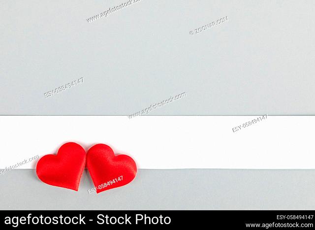 Valentine's day two red silk hearts and white paper on gray paper background, love concept