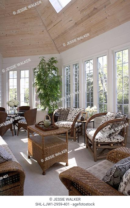 Sunroom with brown wicker furniture, skylight, pattern cushions, windows, beige carpet, wood paneled ceiling, tray with teapot, game table with four chairs