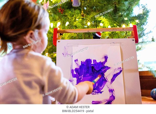 Caucasian girl painting with purple paint on paper