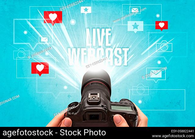 Close-up of a hand taking photos with LIVE WEBCAST inscription, social media concept