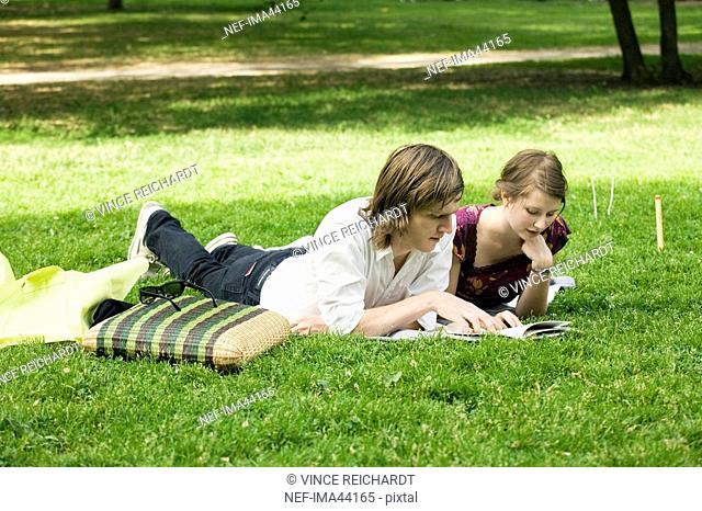 Young Scandinavian couple reading a book together outdoors Sweden