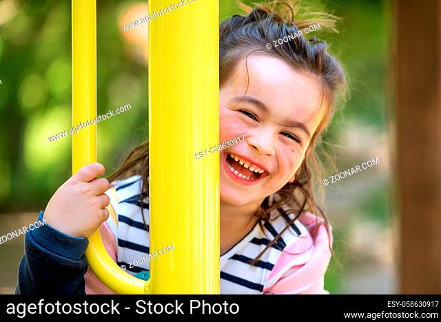 Cute girl enjoying on playground in the park in summertime