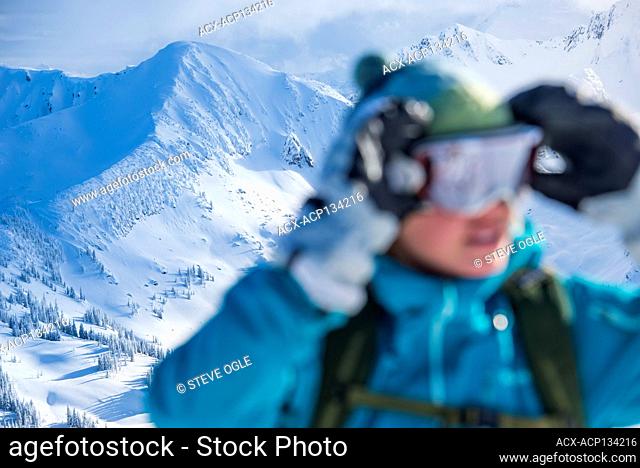 A female skier adjusts her goggles in the Valkyr Range, Burton, British Columbia