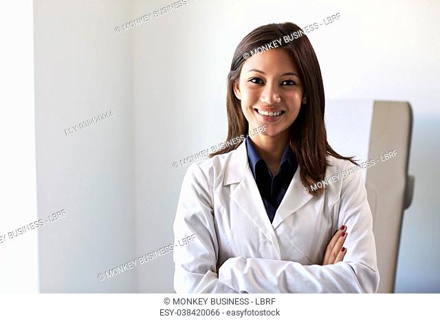 Portrait Of Female Doctor Wearing White Coat In Exam Room