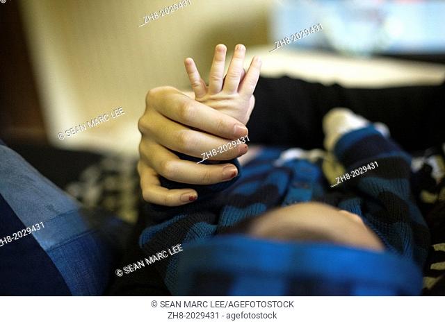 A mother holds a newborn baby's hand