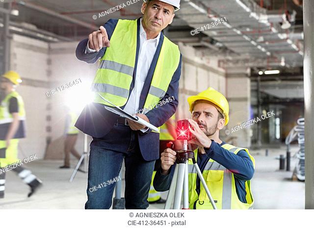 Male foreman and engineer with theodolite at construction site
