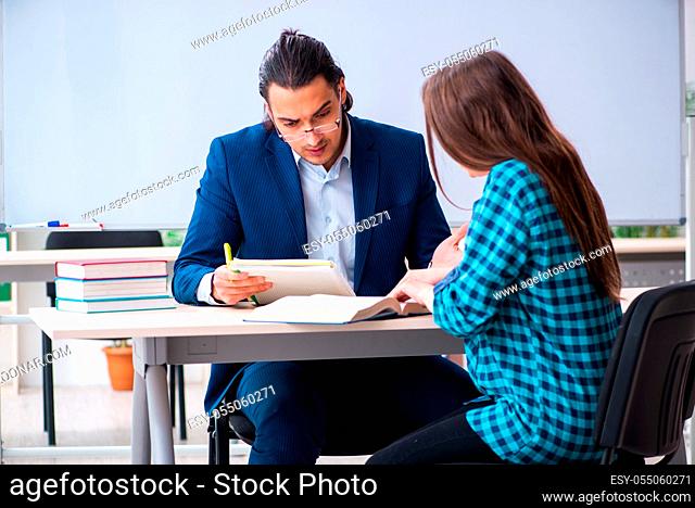 The young handsome teacher and female student in the classroom