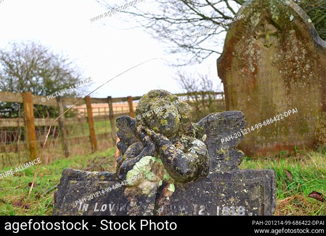 11 December 2020, Great Britain, Ashford: A gravestone in the garden of the small 13th century Sevington Church in Ashford, England