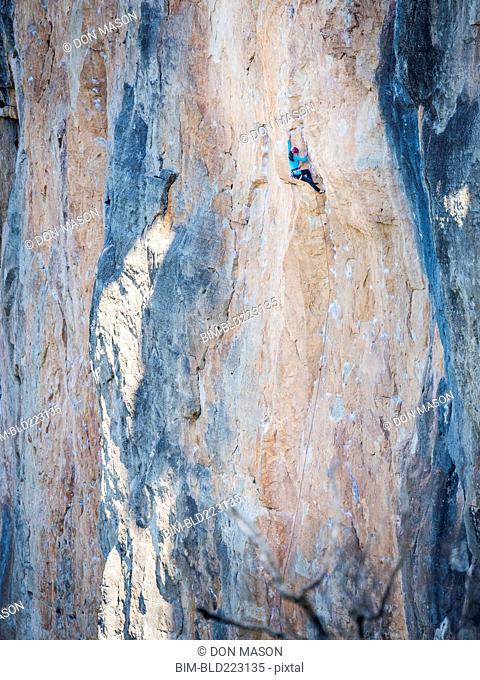 Mixed Race girl climbing rock