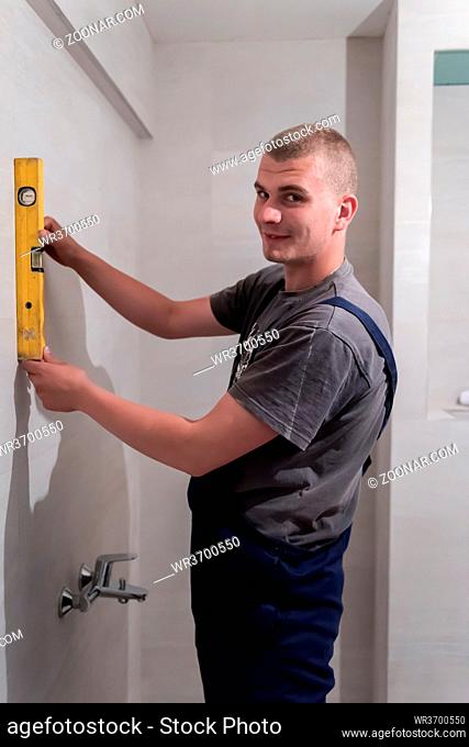 professional plumber using bubble level while working in a bathroom, plumbing repair service, assemble and install concept plumber tools and equipment in a...