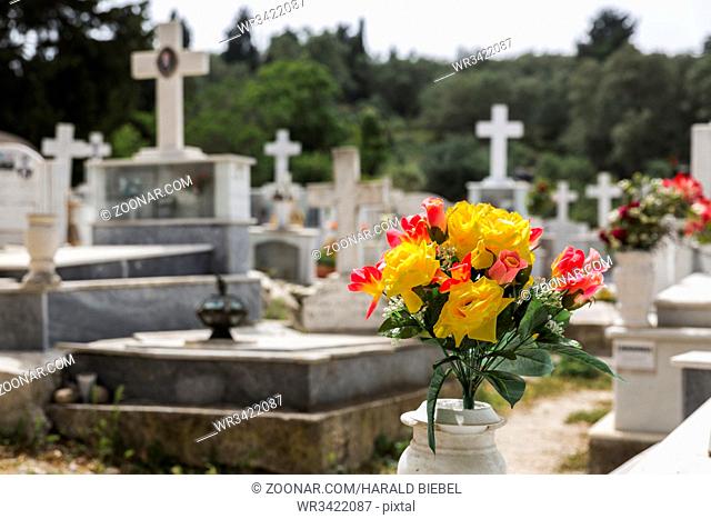 Plastikblumen auf einem Friedhof mit unscharfem Hintergrund