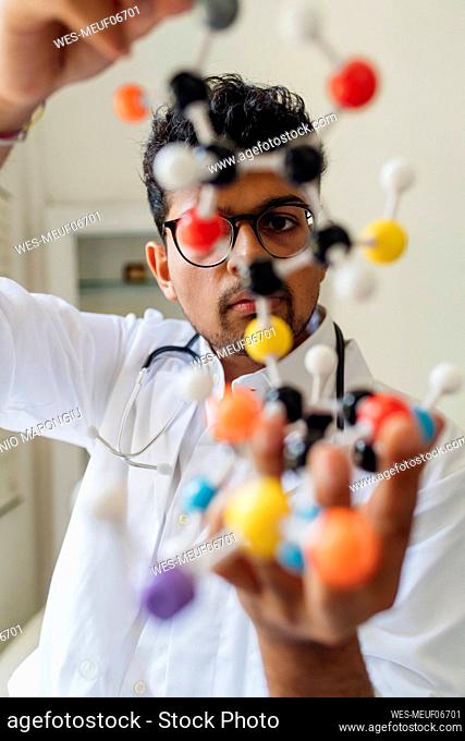 Young scientist examining helix model in laboratory