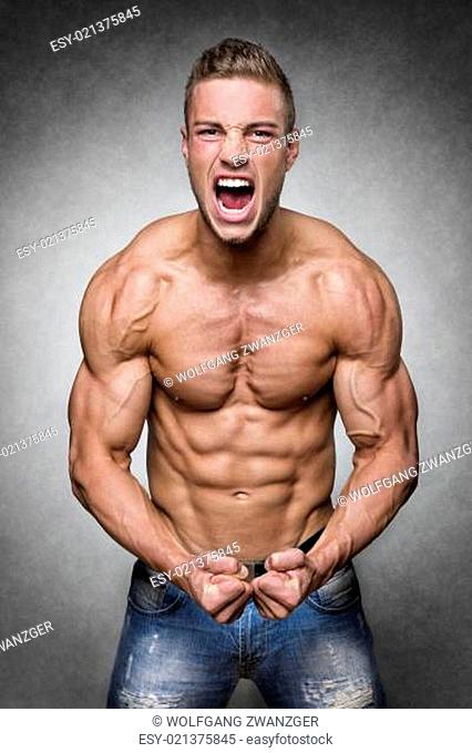 Screaming man with well trained body, biceps, abs and pecs and wearing a denim trousers