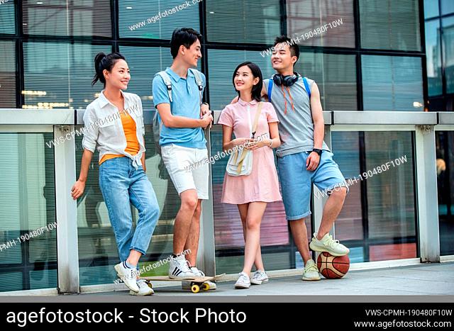 Outdoor happy college students lean on column while standing