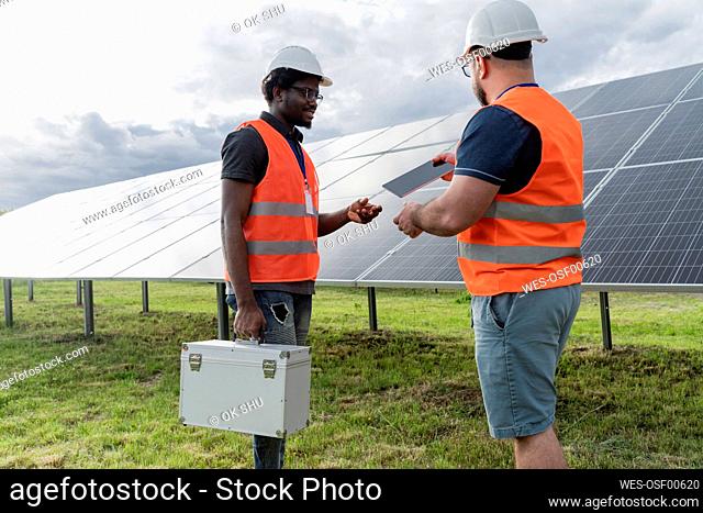 Colleagues discussing over tablet PC at solar station