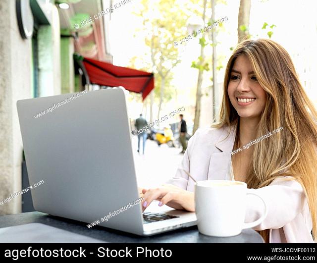 Young woman smiling while working on laptop at cafe
