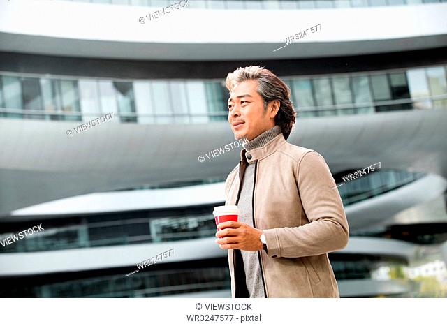 Business man holding a coffee cup to go to work