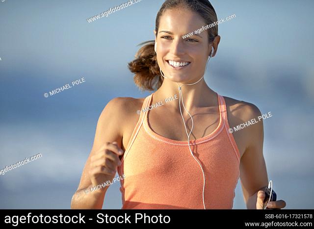 Close up of young woman running and listening to music