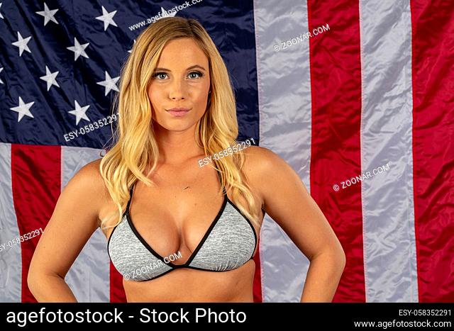 A gorgeous blonde swimsuit model posing against an American Flag in a studio environment