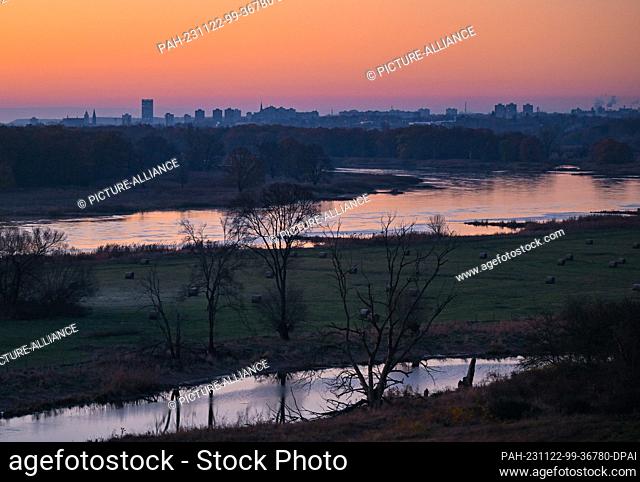 22 November 2023, Brandenburg, Lebus: Sunrise over the Oder, the German-Polish border river, with a view of the city of Frankfurt (Oder) in the background