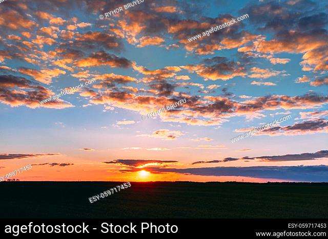 Natural Sunset Sunrise Over Field Meadow. Bright Dramatic Sky And Dark Ground. Countryside Landscape Under Scenic Colorful Sky At Sunset Dawn Sunrise