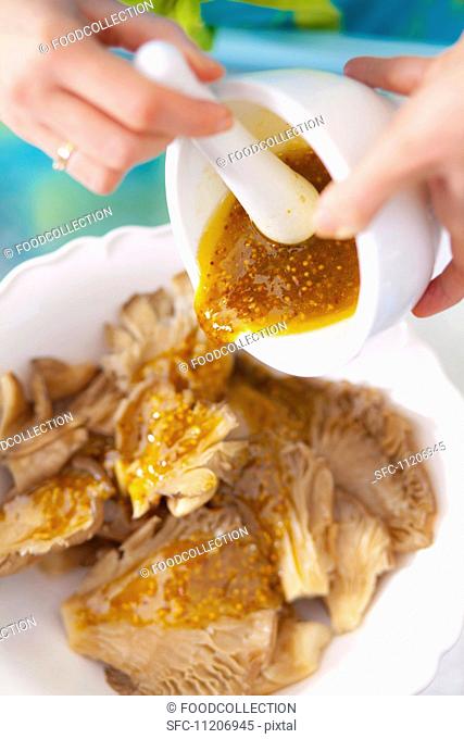 Mustard marinade being poured over oyster mushrooms